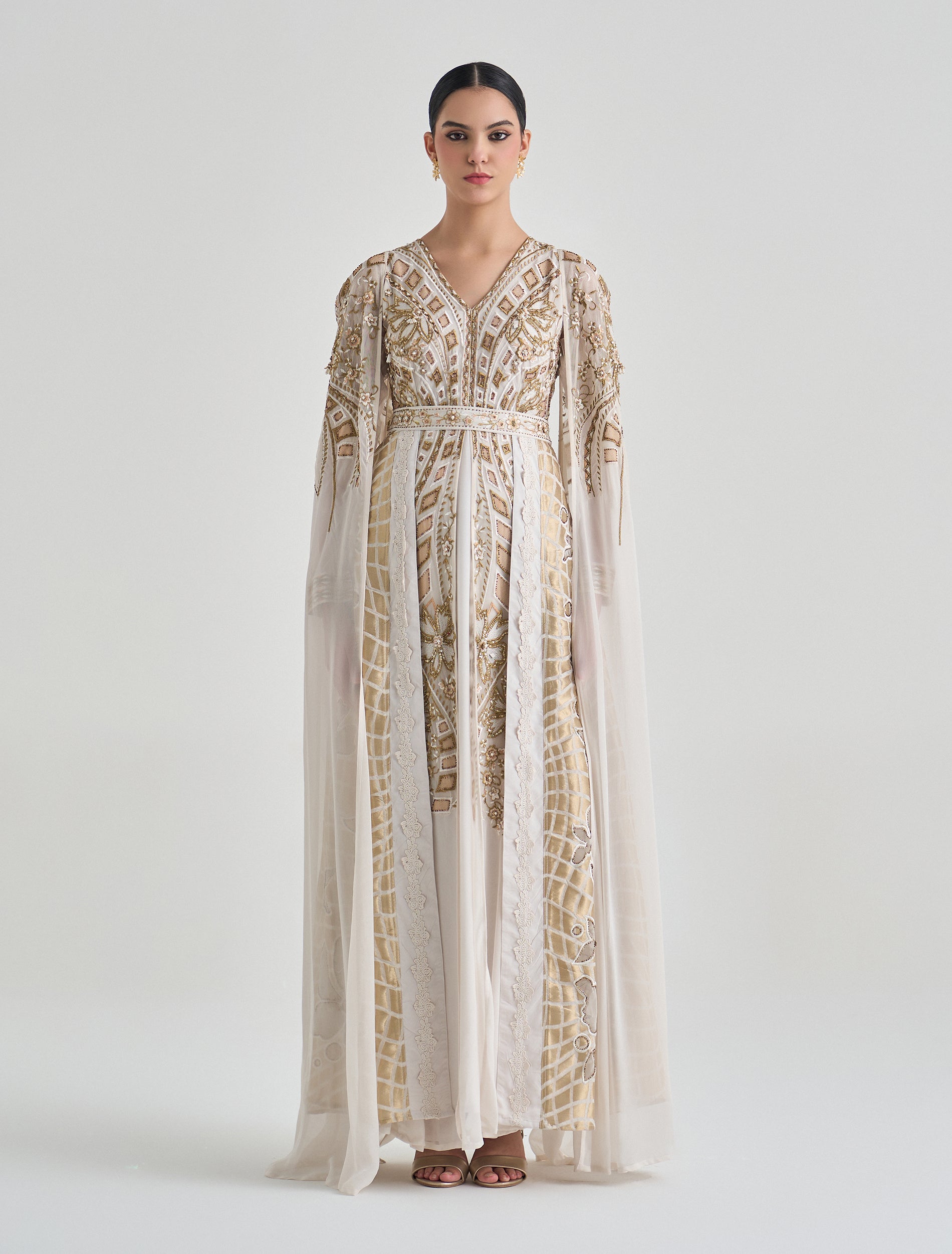Off-white soiree gown with a long embroidered cape and golden accents Off-white soiree gown with a long embroidered cape and golden accents