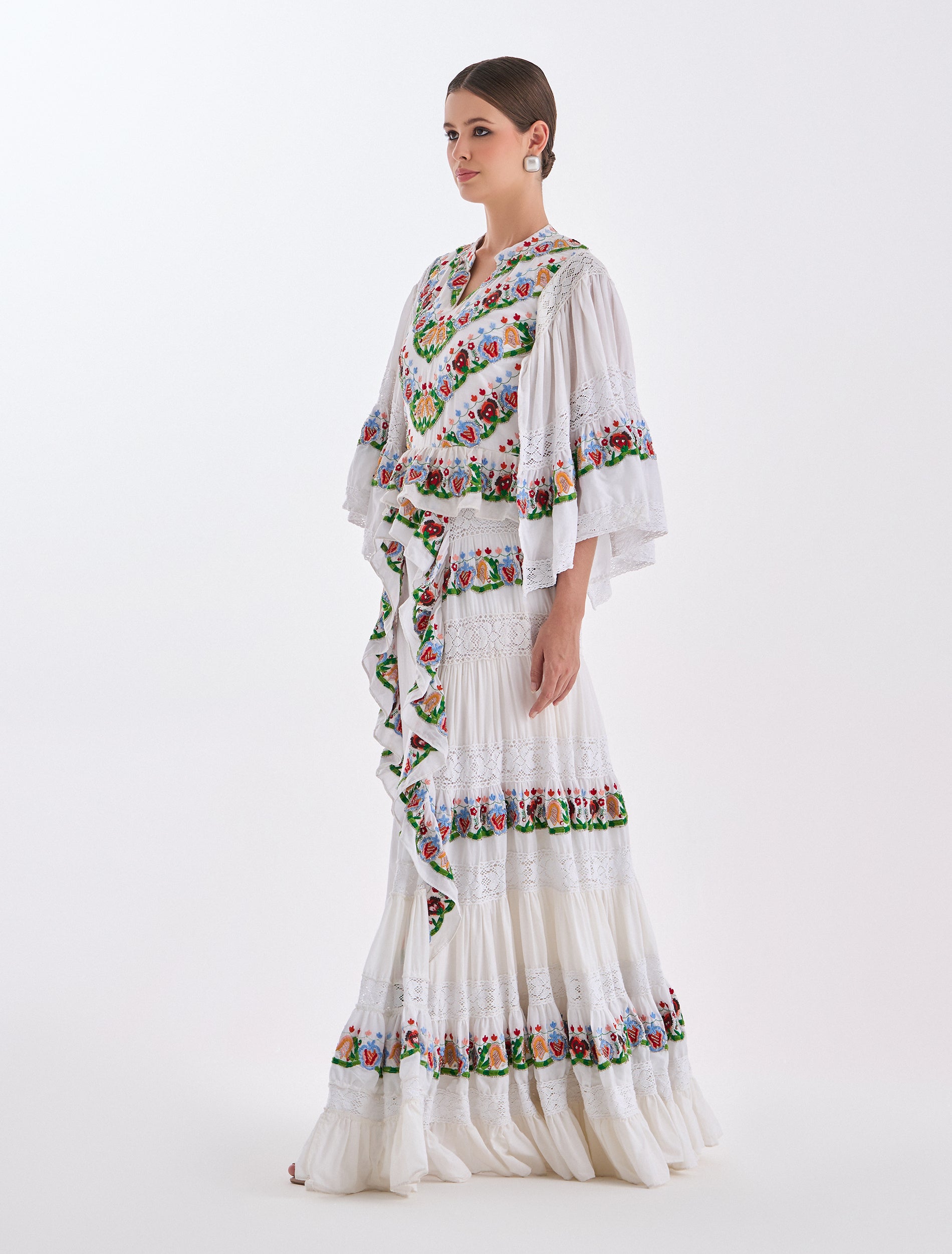 فستان سهرة ناعم بتصميم كشكش طبقات من الدانتيل مع تطريزات ملونة
A white evening dress with layered ruffles in lace and vibrant embroidery